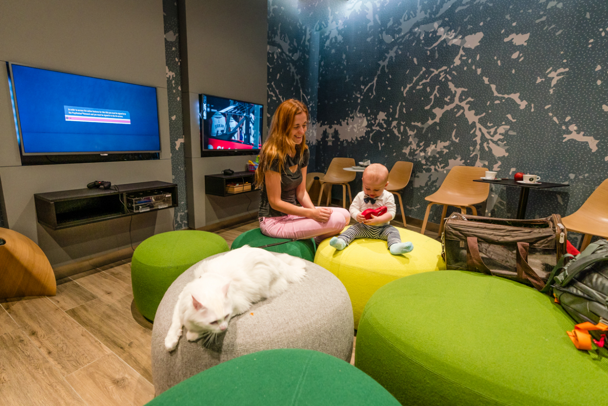 Relaxed airport lounge setting with a mother and baby playing, reflecting on the smoother aspects of flying with a baby.