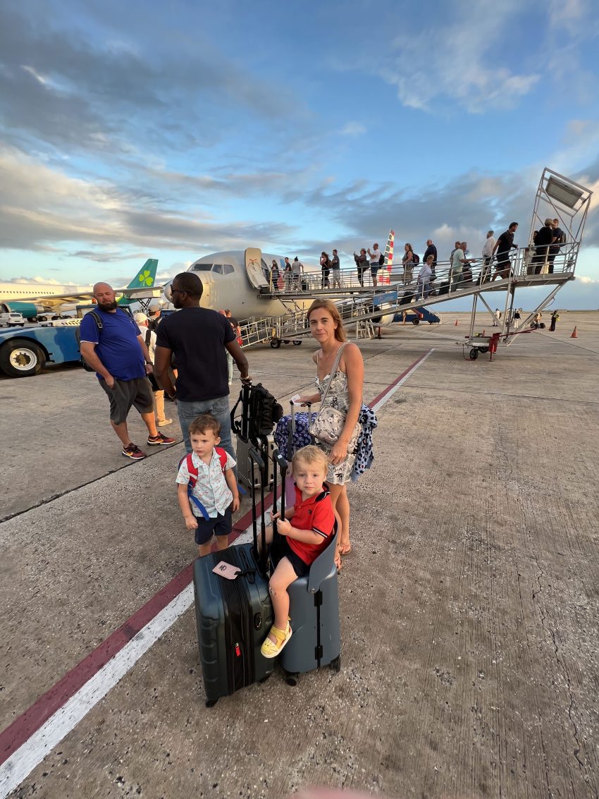 Family ready for boarding, with a child comfortably seated on a ride-on suitcase, making airport waits enjoyable and restful.