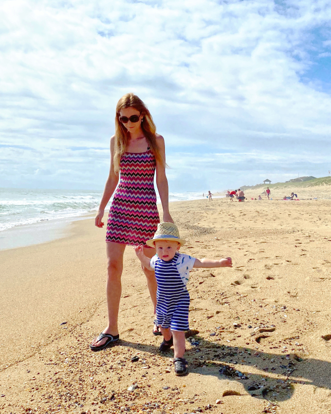 Mother and toddler in matching straw hats on a sandy beach, a beautiful and baby-friendly travel destination in the US.